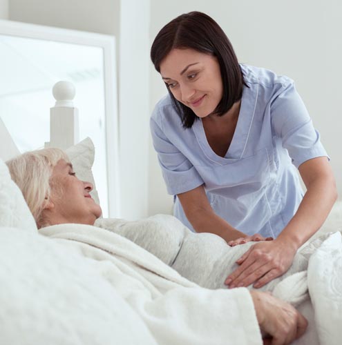 home health aide comforting senior woman with gastrointestinal pain