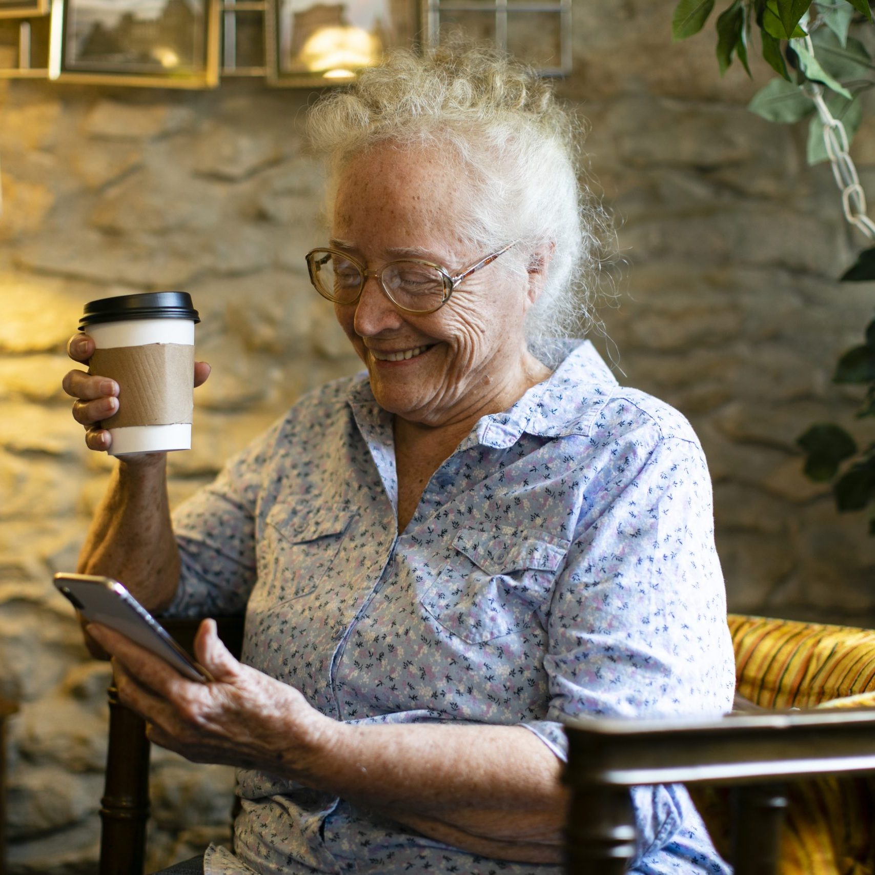 Sweet senior woman using her phone at a cafe senior citizen's gateway