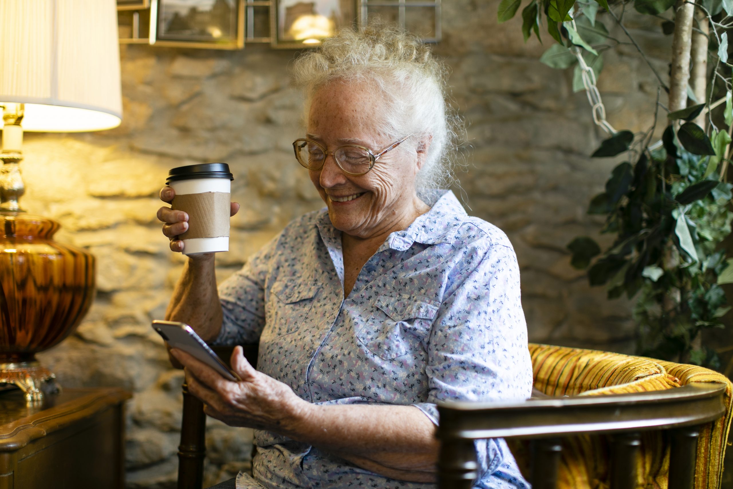 Sweet senior woman using her phone at a cafe senior citizen's gateway