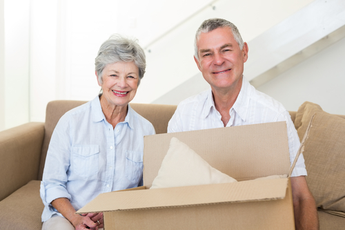 Cheerful senior couple moving into new home smiling at camera reducing stress to move an elderly loved one