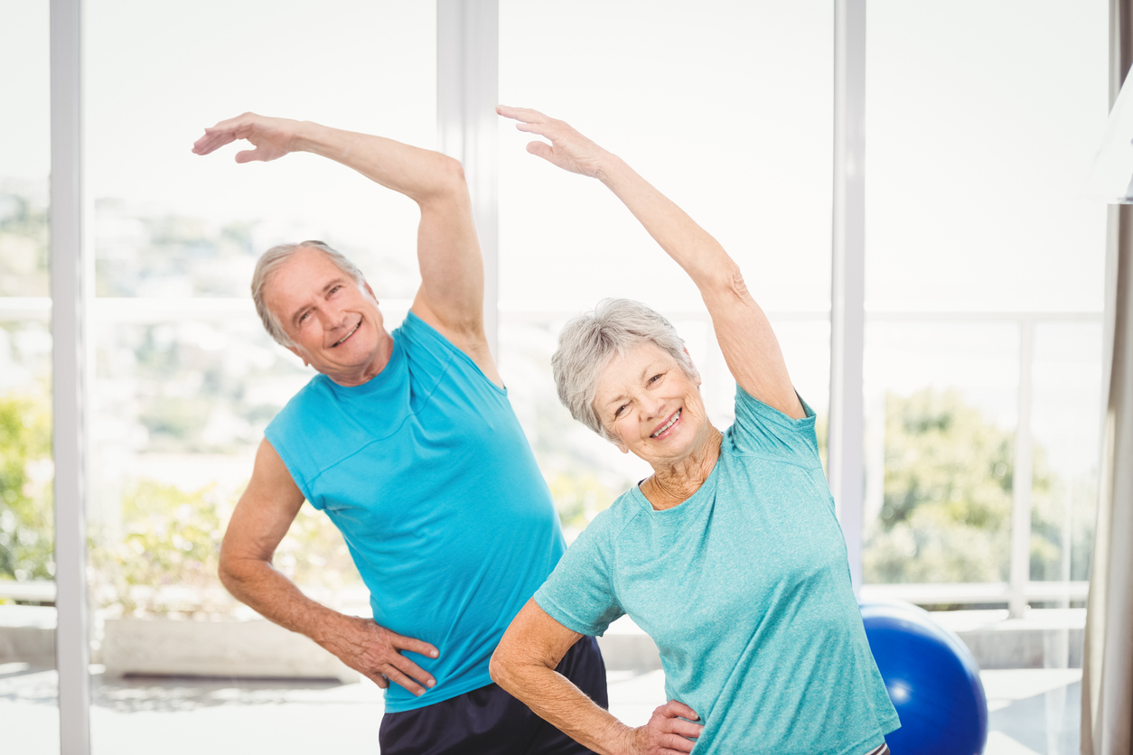 Portrait of smiling senior couple exercising at home
