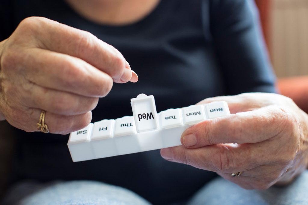 Senior Woman Taking Medication From Pill Box. Aging and medication concept