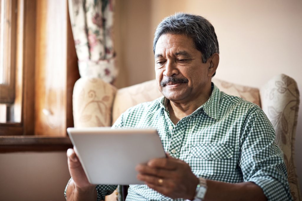 Shot of a senior man using his digital tablet while relaxing at home, use of technology to improve quality of life