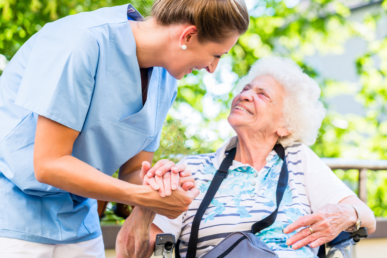 Nurse holding hand of senior woman in pension home aging in place