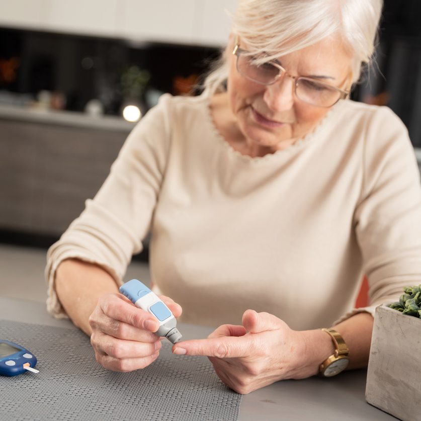 A senior woman with geriatric diabetes checking her blood glucose levels.