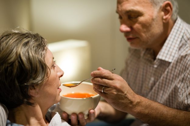 Caring senior man feeding his sick wife health issue of spouses of stroke victims