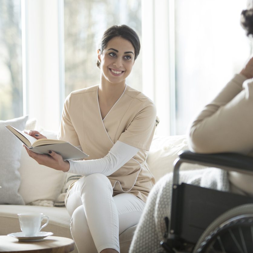 COVID-19 and heart disease in Staten Island; caregiver reading to senior in Staten Island.