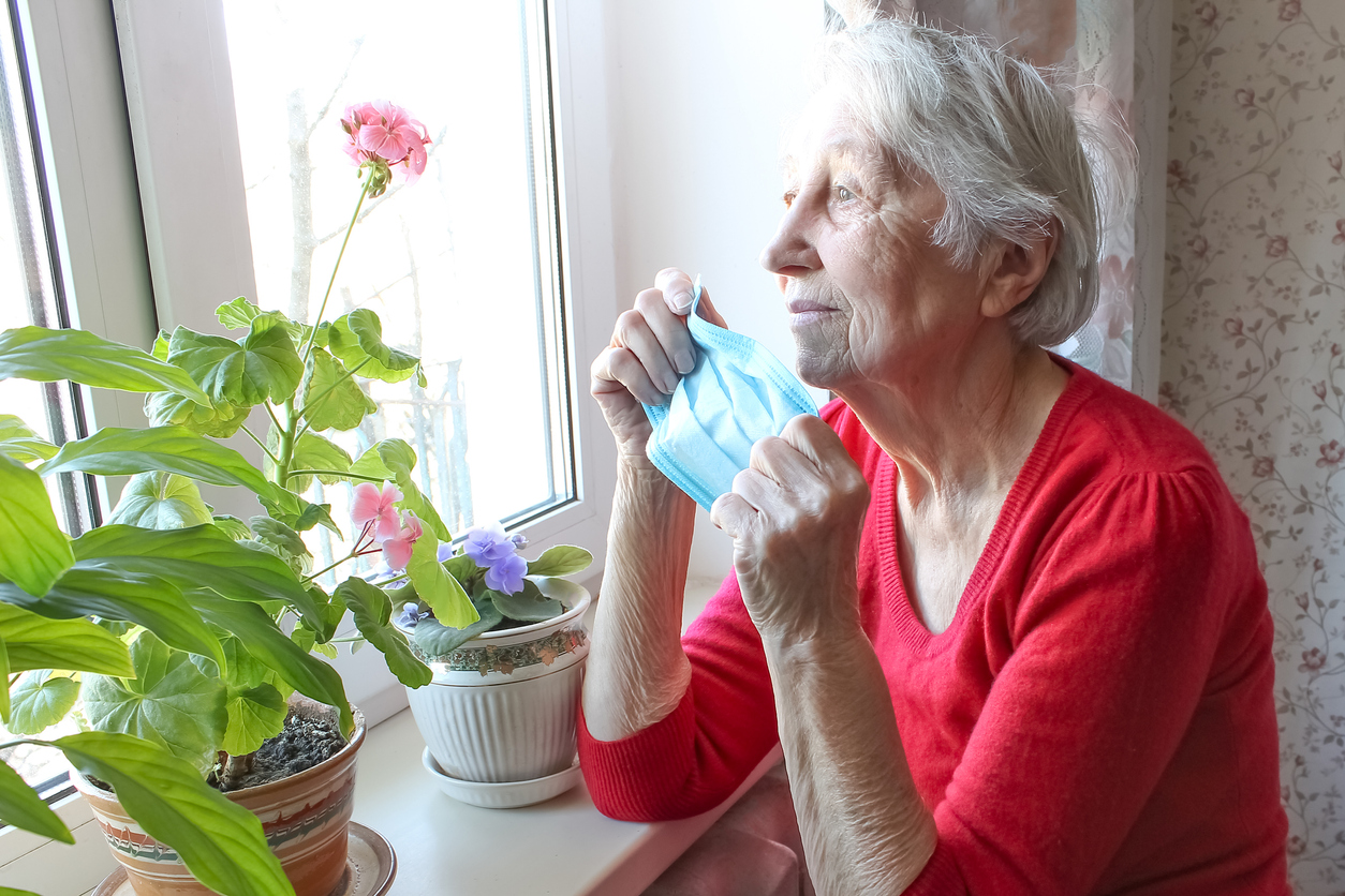Lonely Senior Woman at Home in the Bronx lonely senior woman at home sitting by the window sill; COVID-19 isolation in the Bronx.
