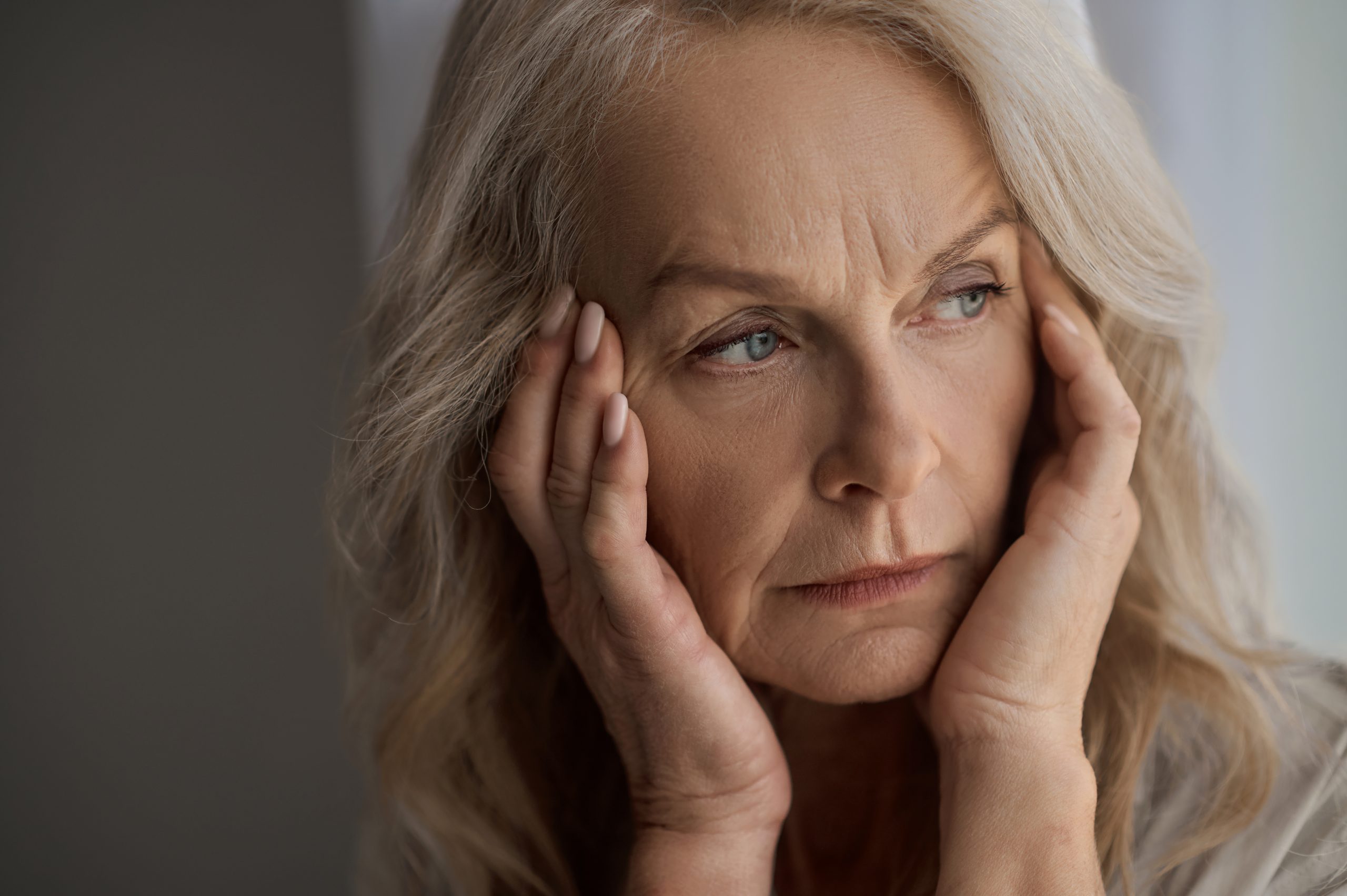 Sad mature woman suffering from a headache taking caregiver stress seriously as trends continue to climb