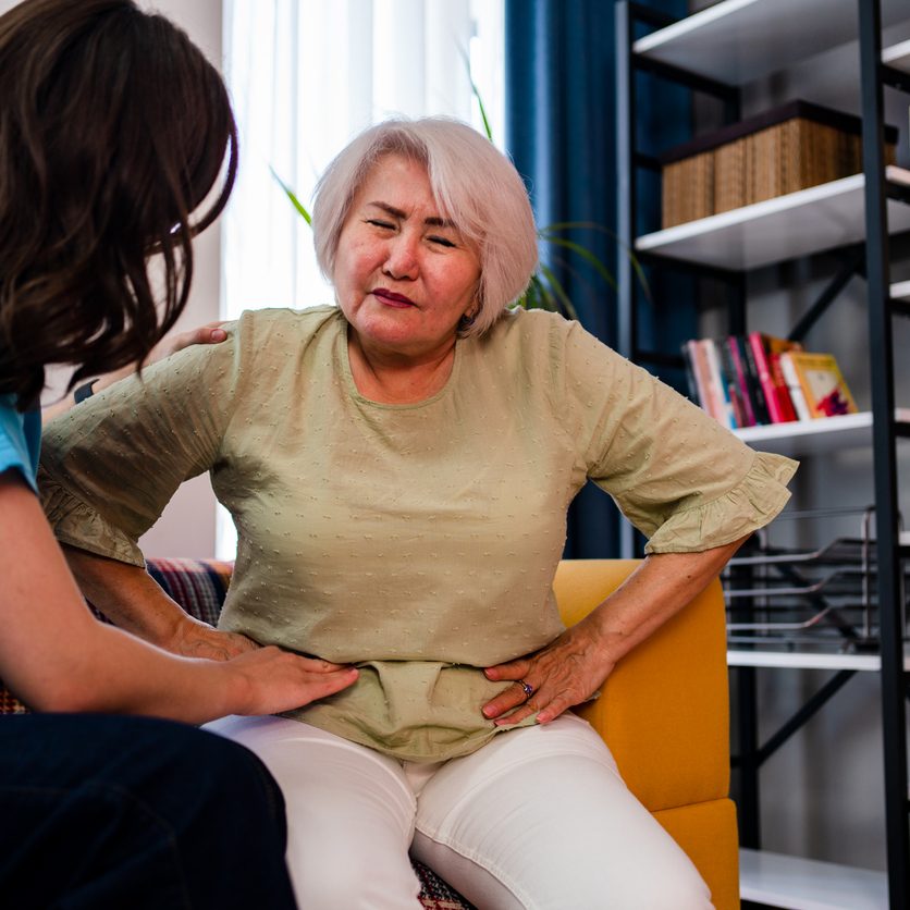 Elderly woman explains GERD pain to caregiver in Nassau County.