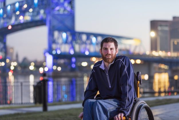 Man in a wheelchair with Cerebral Palsy on city waterfront.