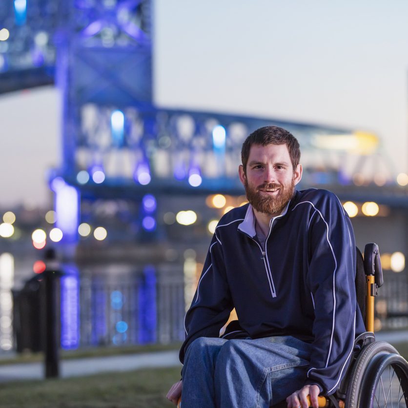 Man in a wheelchair with Cerebral Palsy on city waterfront.