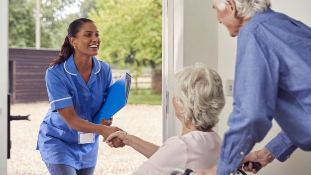 An elderly couple welcomes their home health aide.