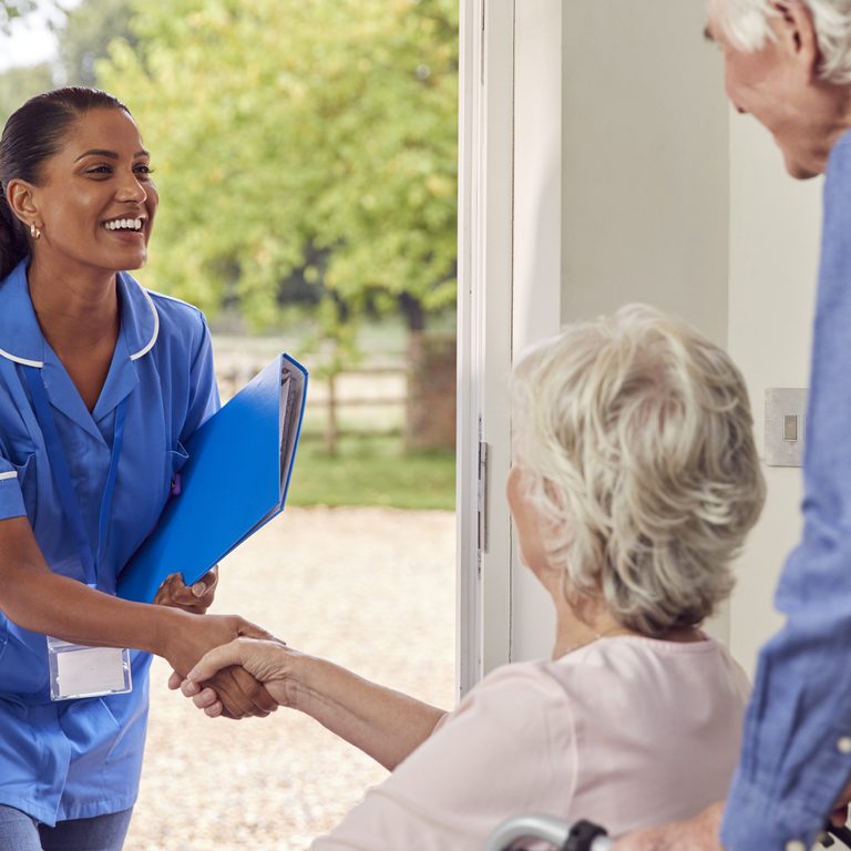 An elderly couple welcomes their home health aide.