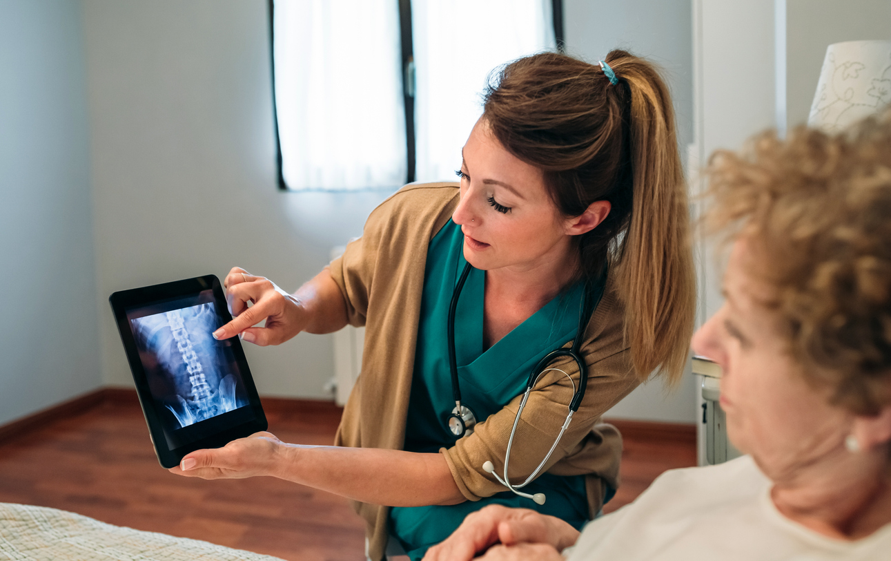 A doctors shows her elderly patient the results of her bone density test.